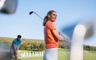 Zwei Personen spielen Golf auf einem Golfplatz.