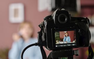 Eine Person sitzt vor einer Kamera und nimmt ein Video auf.